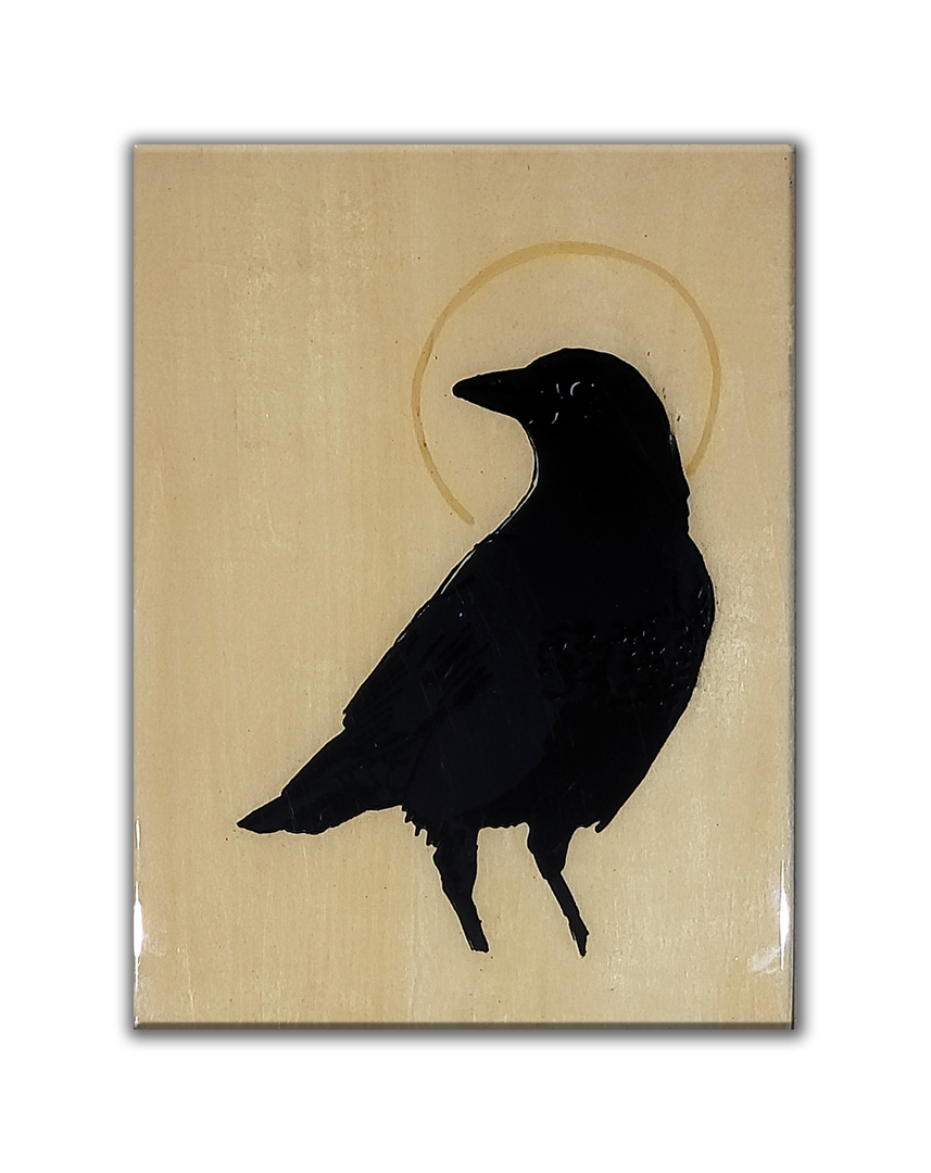 A screenprint of a crow looking over its shoulder with a golden halo. The print is on a wood canvas